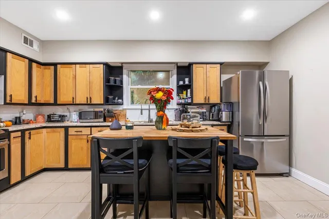 a kitchen with stainless steel appliances a table chairs refrigerator and sink