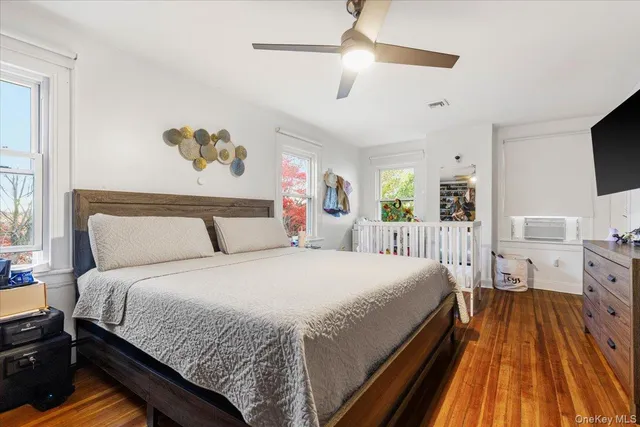 a spacious bedroom with a bed and a flat tv screen on dresser
