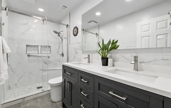 a bathroom with a granite countertop sink a toilet and a shower