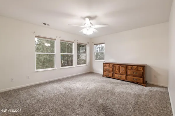an empty room with windows and fan