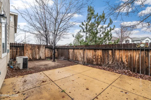 a view of a backyard with large trees and wooden fence
