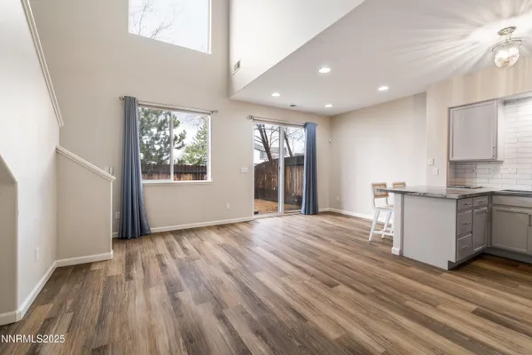 a view of an empty room with window and wooden floor