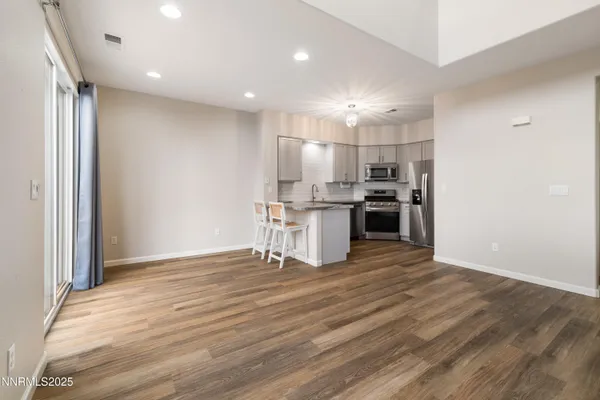 a view of kitchen with kitchen island wooden floor appliances and cabinets