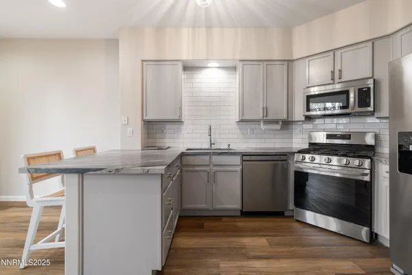 a kitchen with stainless steel appliances granite countertop a stove a sink and a microwave