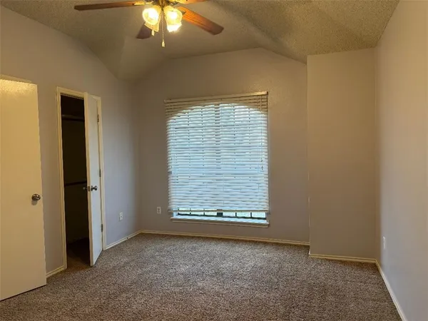 an empty room with a window and chandelier fan