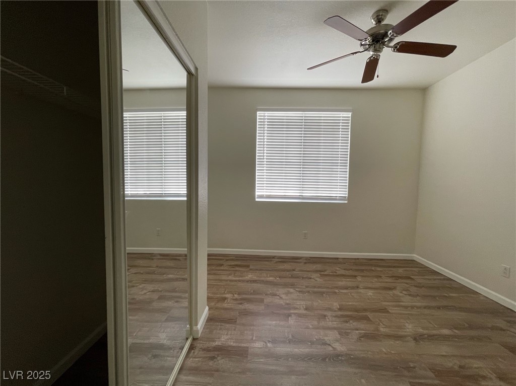 10217 King Henry Avenue, Unit 104 Las Vegas, NV 89144 - Photo 12 of 18 Unfurnished bedroom with dark wood-style floors, multiple windows, a ceiling fan, and a closet