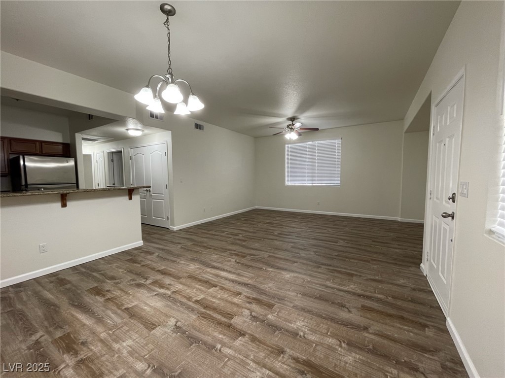 10217 King Henry Avenue, Unit 104 Las Vegas, NV 89144 - Photo 6 of 18 Unfurnished living room with dark wood-style flooring, a chandelier, and ceiling fan