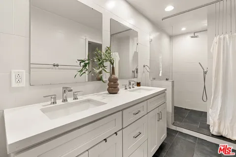 a bathroom with a double vanity sink mirror and shower