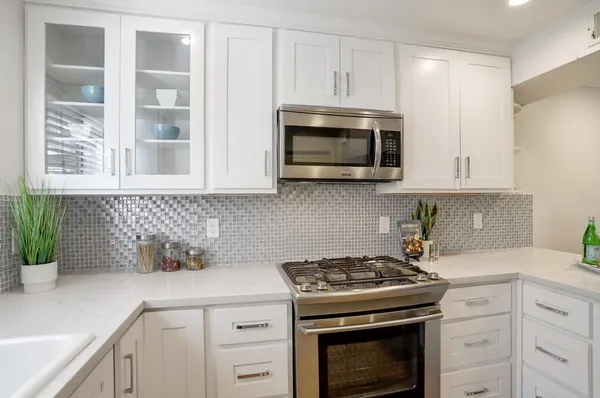 a kitchen with granite countertop white cabinets and stainless steel appliances