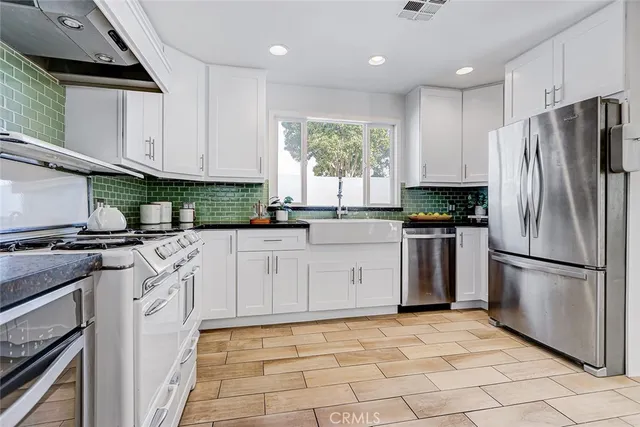 a kitchen with granite countertop a refrigerator stove top oven and sink