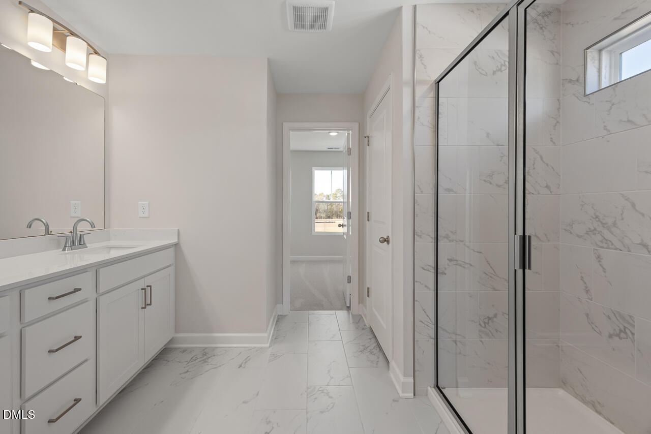 233 Tenure Lane Lillington, NC 27546 - Photo 19 of 30 a spacious bathroom with a granite countertop sink a mirror and a shower