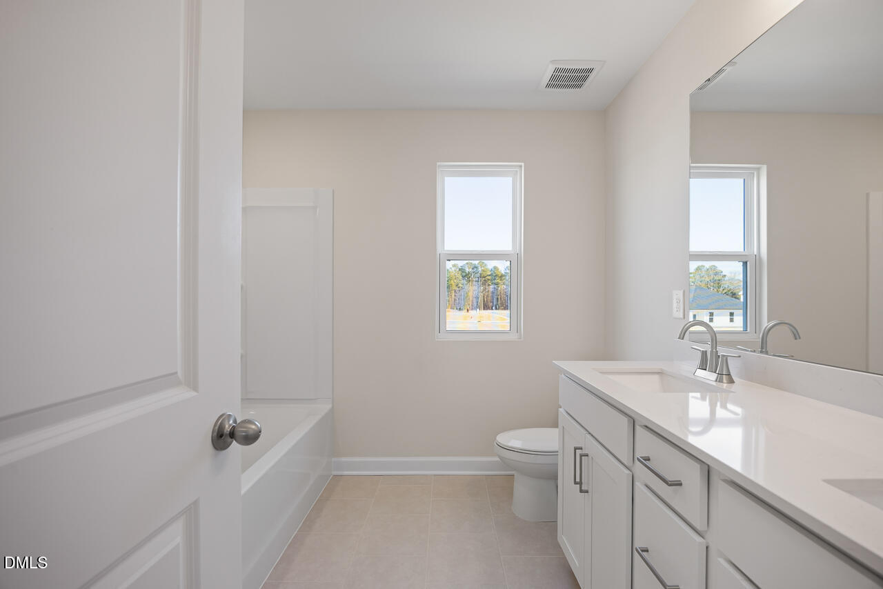 233 Tenure Lane Lillington, NC 27546 - Photo 25 of 30 a bathroom with a granite countertop sink a toilet and shower