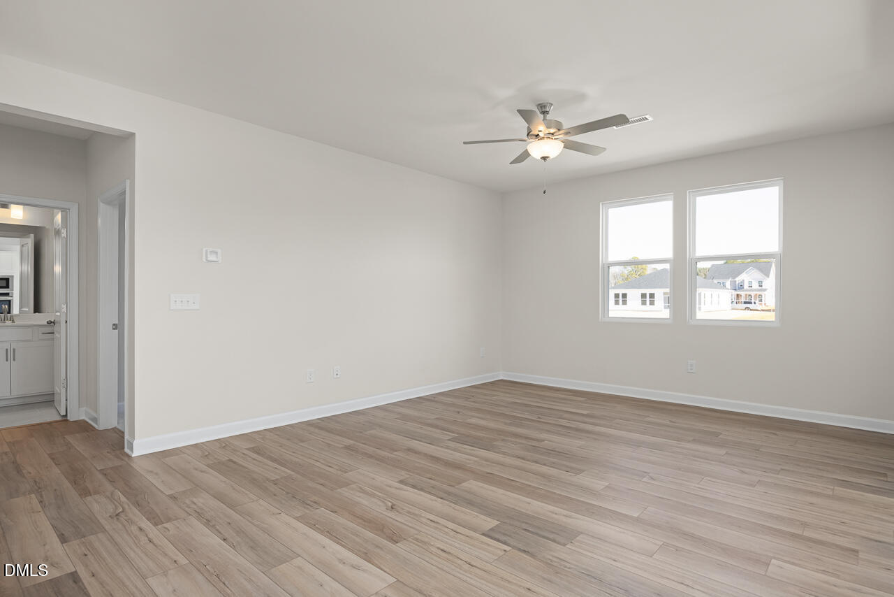 233 Tenure Lane Lillington, NC 27546 - Photo 6 of 30 an empty room with wooden floor ceiling fan and windows