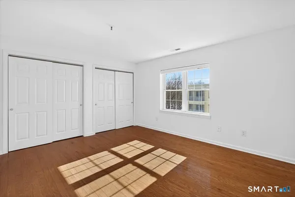 an empty room with wooden floor cabinet and windows