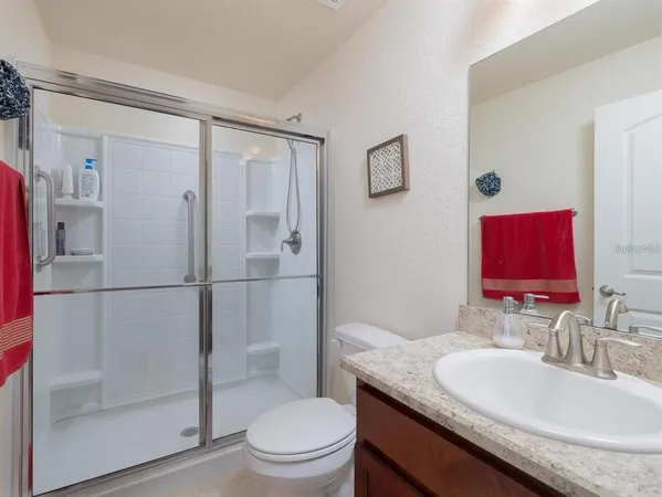 a bathroom with a granite countertop toilet sink shower and mirror
