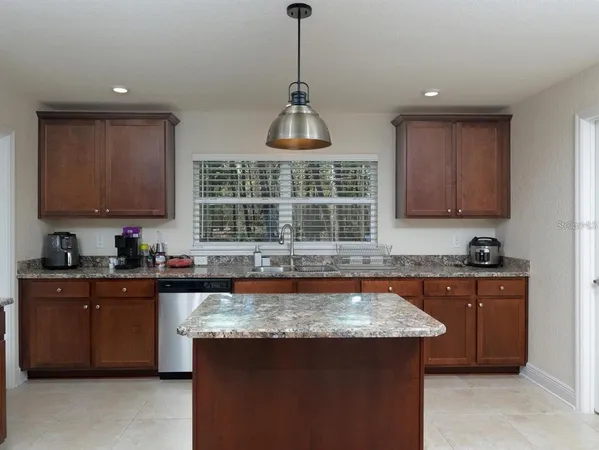 a kitchen with kitchen island granite countertop a stove a sink dishwasher and cabinets with wooden floor