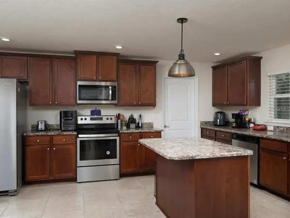 a kitchen with kitchen island granite countertop stainless steel appliances a stove sink microwave and cabinets