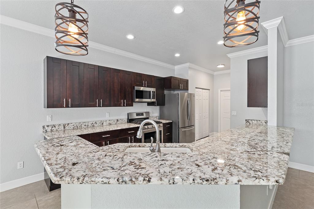 4765 Southeast 25th Street Ocala, FL 34480 - Photo 16 of 65 a kitchen with stainless steel appliances kitchen island granite countertop a sink refrigerator and microwave