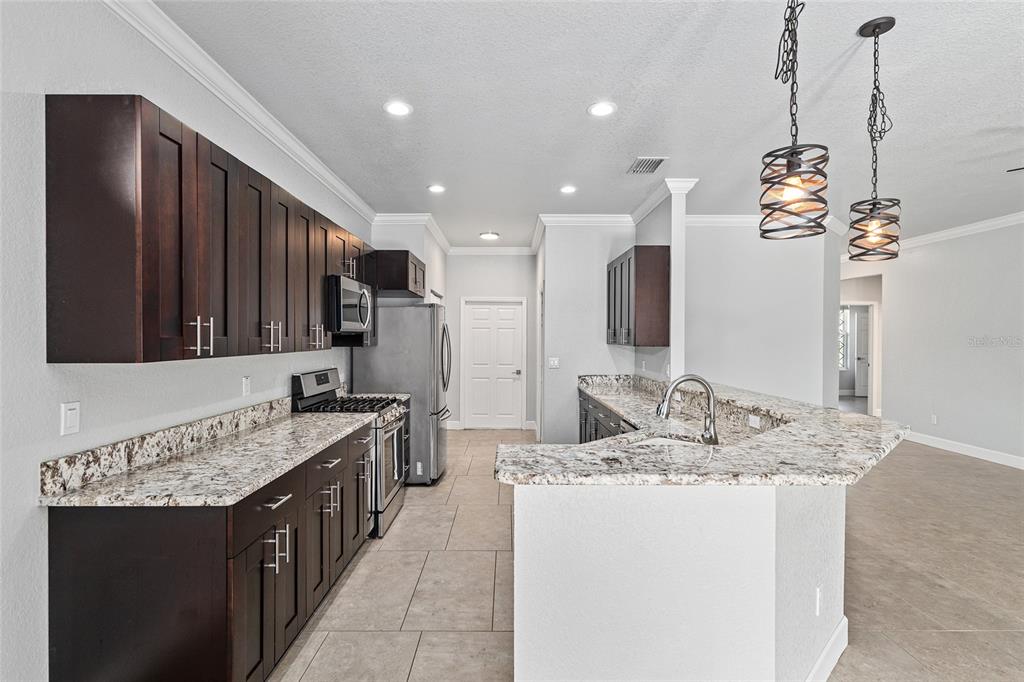 4765 Southeast 25th Street Ocala, FL 34480 - Photo 17 of 65 a kitchen with kitchen island granite countertop a sink and a refrigerator