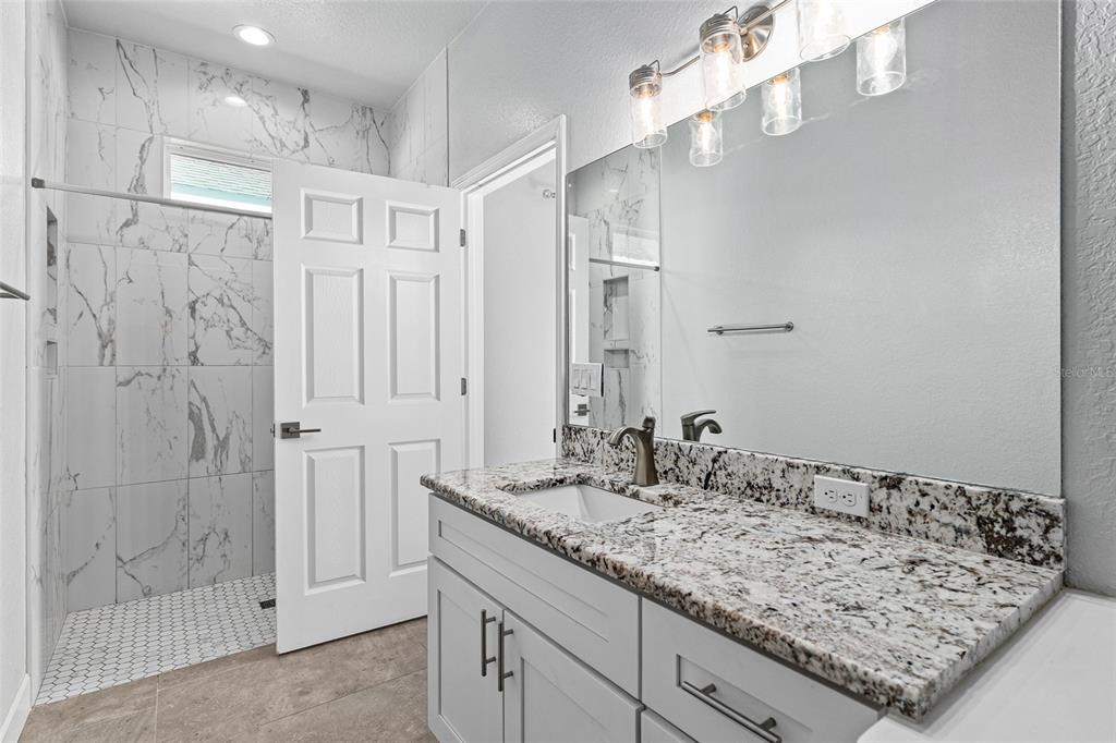 4765 Southeast 25th Street Ocala, FL 34480 - Photo 30 of 62 a bathroom with a granite countertop sink a mirror and shower