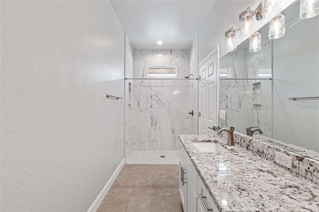 4765 Southeast 25th Street Ocala, FL 34480 - Photo 31 of 62 a bathroom with a granite countertop sink a mirror and shower