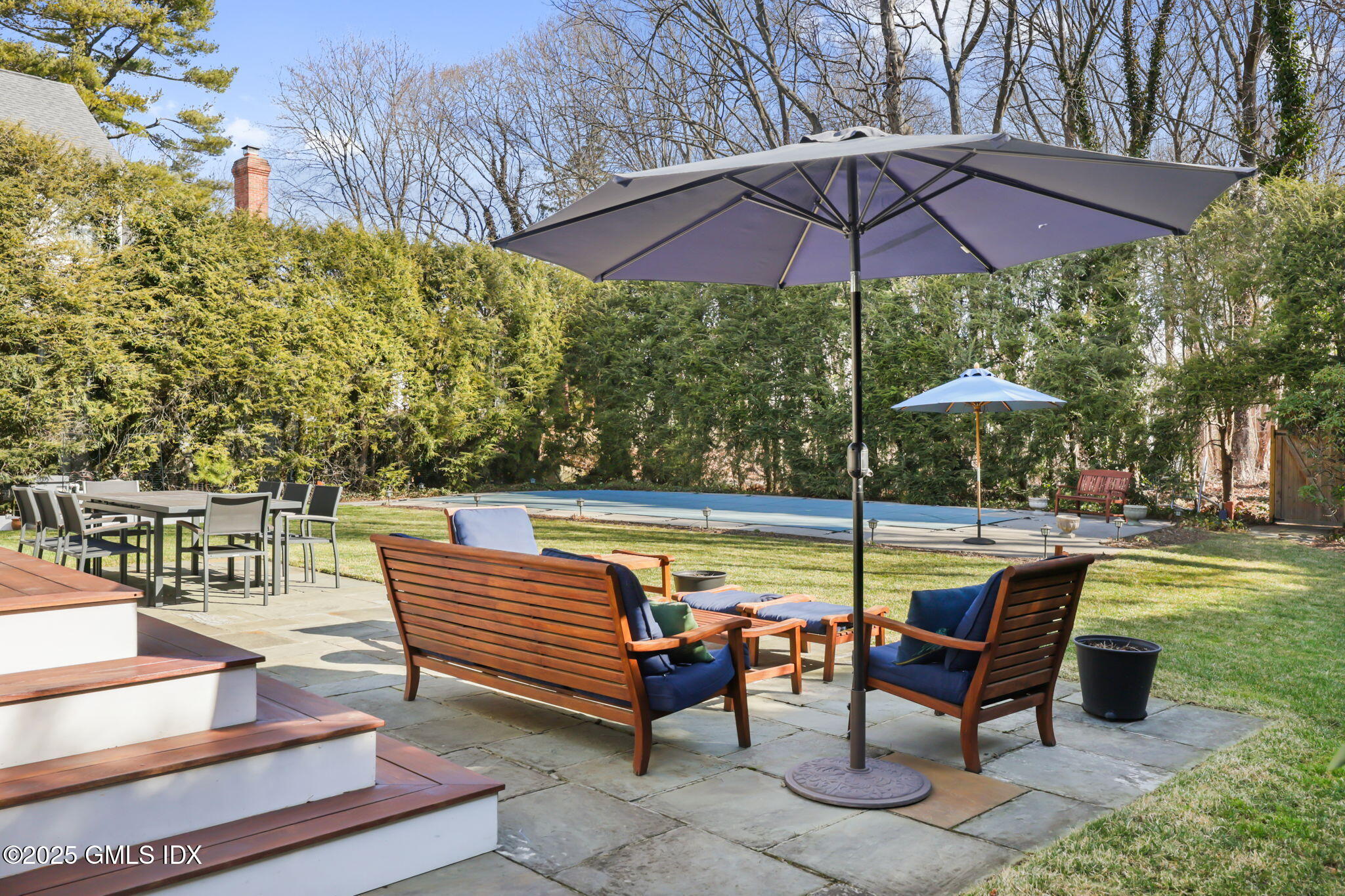 35 Indian Field Road Greenwich, CT 06830 - Photo 1 of 38 a view of a swimming pool with a table and chairs under an umbrella
