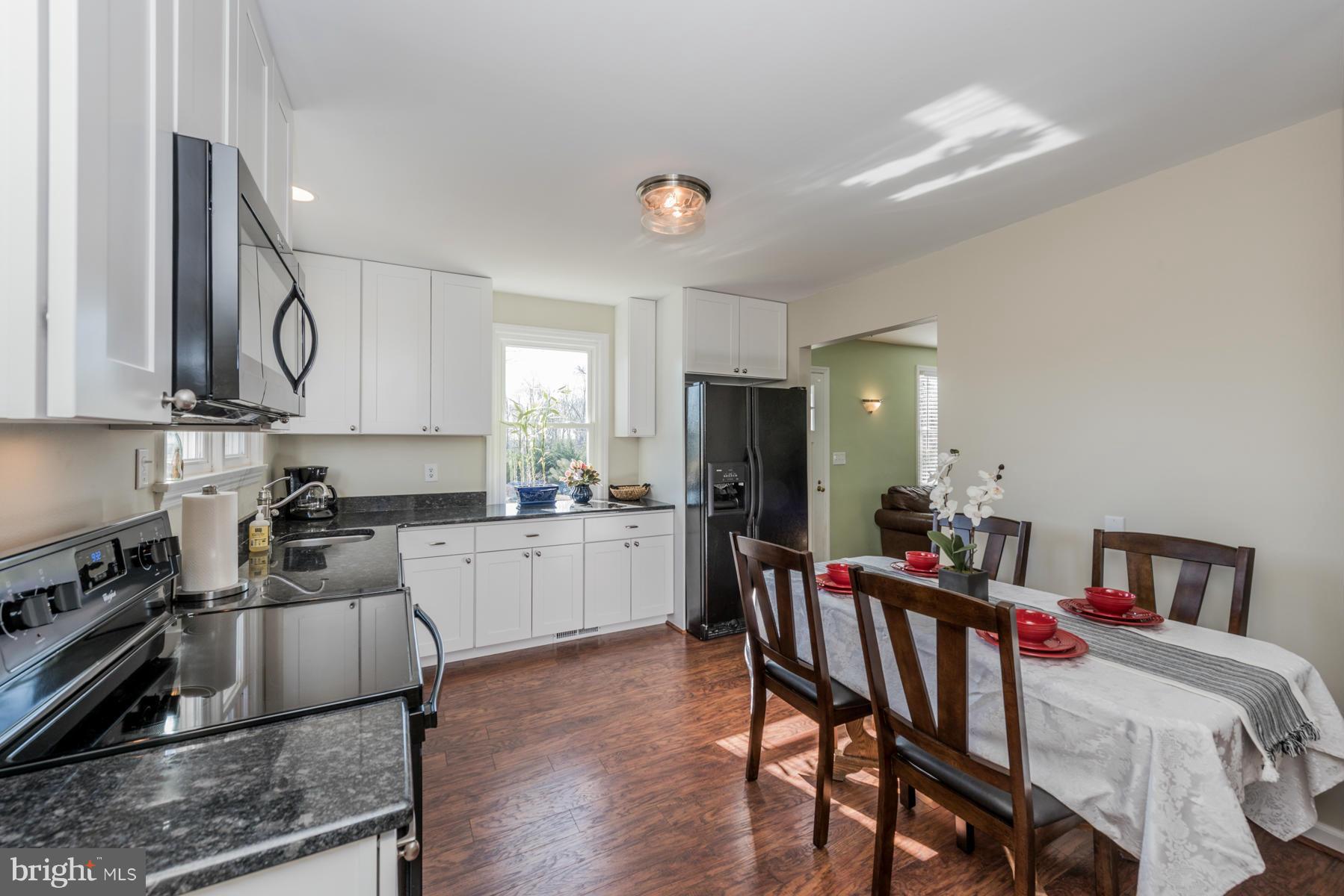 15103 Parrish Road Upperco, MD 21155 - Photo 7 of 26 a kitchen with stainless steel appliances granite countertop a stove a refrigerator a kitchen island a dining table and chairs with wooden floor