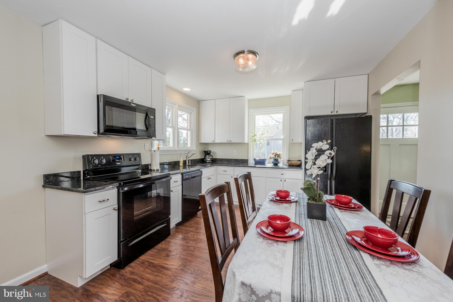 15103 Parrish Road Upperco, MD 21155 - Photo 10 of 26 a kitchen with stainless steel appliances granite countertop a stove refrigerator a sink dishwasher and a dining table with wooden floor