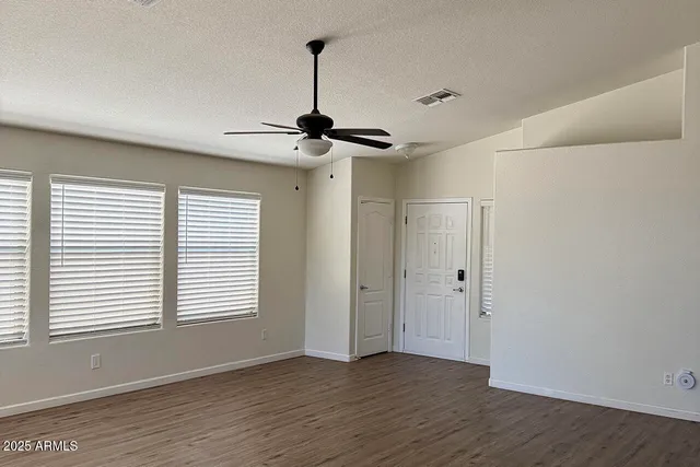 a view of an empty room with a window and wooden floor