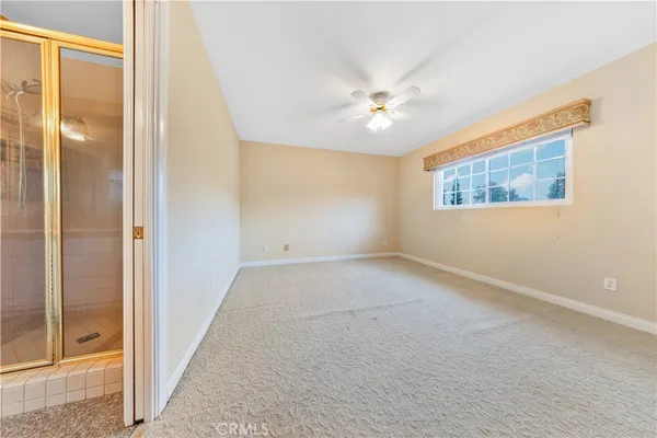 an empty room with a chandelier fan and windows