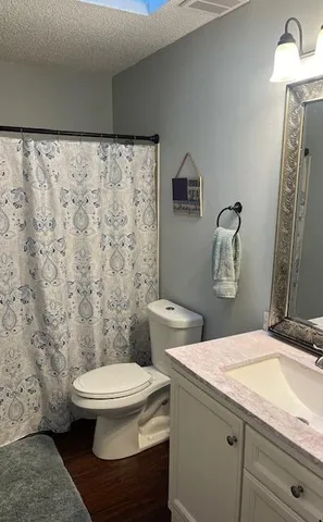 a bathroom with a granite countertop toilet and a sink
