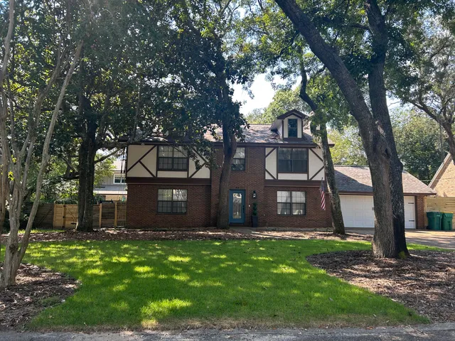 a front view of a house with a tree and a garden