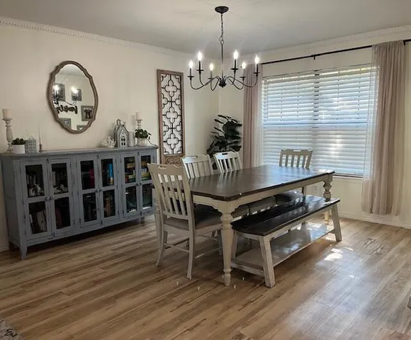a dining room with wooden floor a chandelier a wooden table and chairs