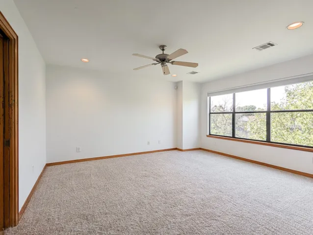 an empty room with chandelier fan and windows