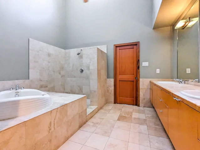a spacious bathroom with a tub sink and mirror