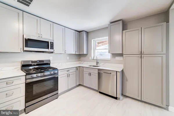 a kitchen with granite countertop white cabinets and stainless steel appliances