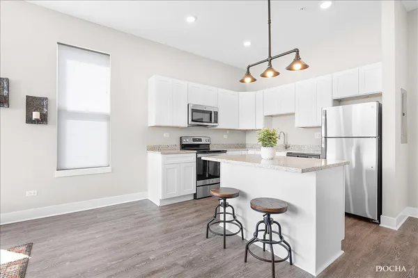 a kitchen with a refrigerator a stove top oven a sink dishwasher and white cabinets with wooden floor