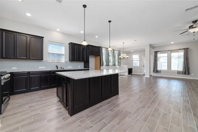 a kitchen with stainless steel appliances granite countertop wooden cabinets a counter top a sink and a wooden floors