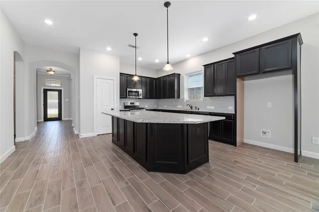 a kitchen with kitchen island stainless steel appliances a sink cabinets and wooden floor