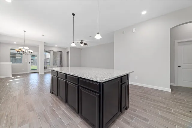 an empty room with wooden floor and kitchen view