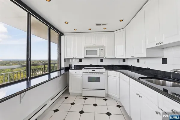 a kitchen with a stove a sink and white cabinets