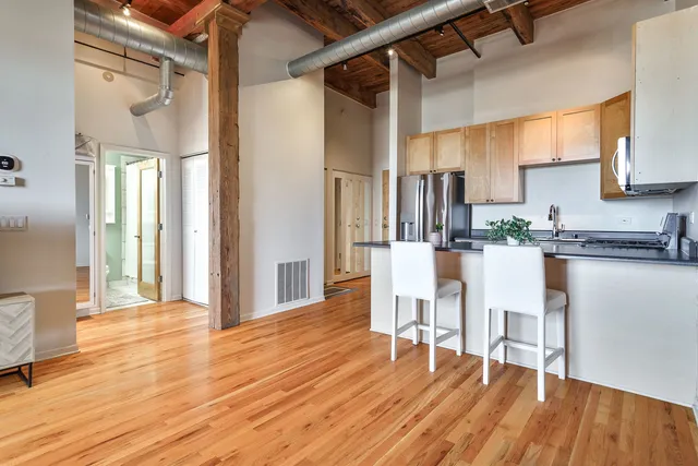 a kitchen with stainless steel appliances granite countertop a refrigerator a stove and white cabinets with wooden floors