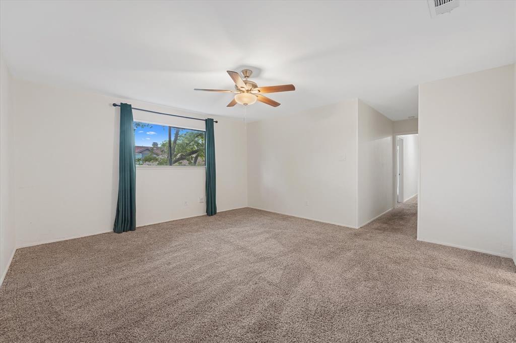 4007 Ridgebrook Drive Arlington, TX 76015 - Photo 12 of 18 Spacious room featuring neutral carpet flooring, light-toned walls, a ceiling fan with integrated lighting, and a large window providing natural light