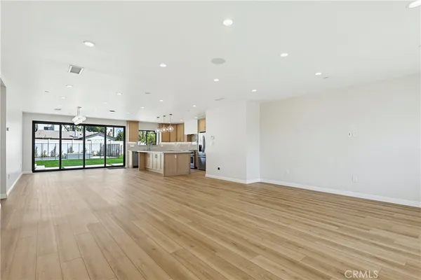 a view of an empty room with wooden floor and windows