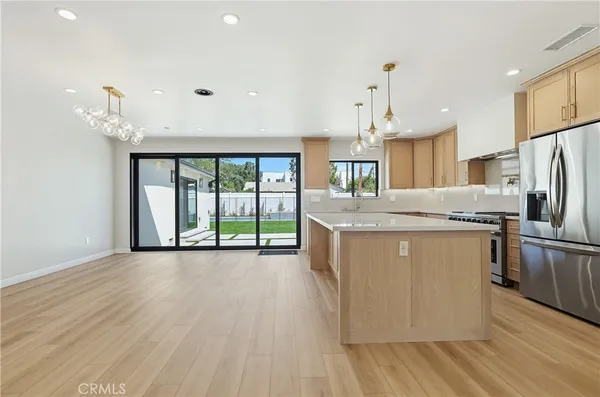 a kitchen with stainless steel appliances granite countertop a refrigerator a sink dishwasher and a fireplace with wooden floor