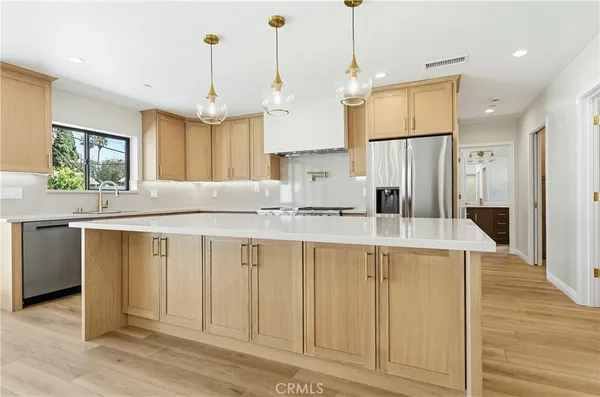 a kitchen with kitchen island granite countertop a sink a counter space and stainless steel appliances