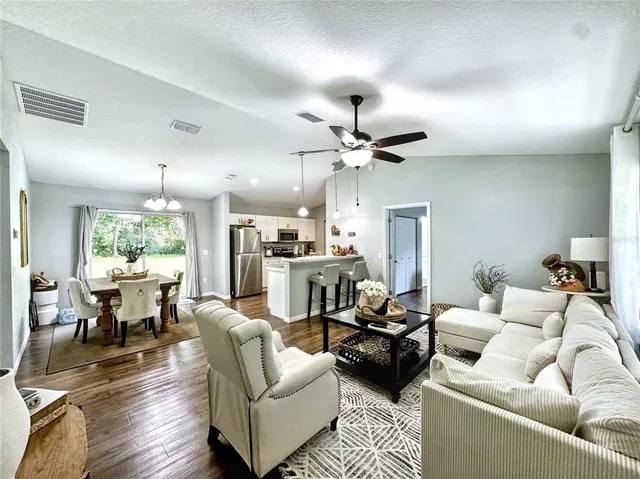a living room with furniture kitchen view and a large window