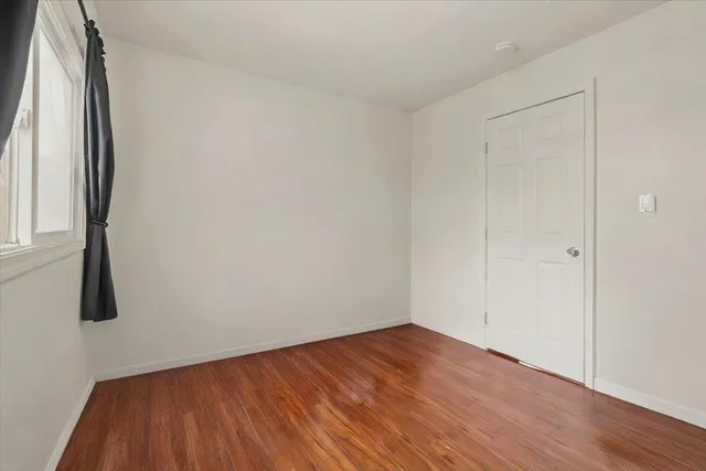 a view of a room with wooden floor and a window