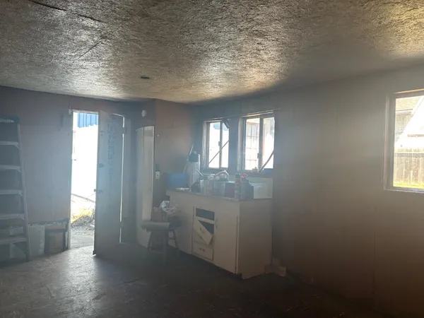 a view of an empty room with wooden floor and windows