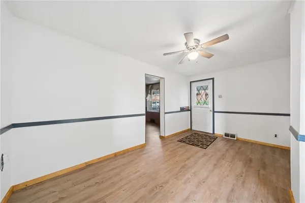 a view of a room with wooden floor and a ceiling fan